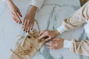 two women touching golden jewelry on marble floor